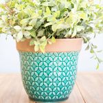 No centro, arranjo de eucalipto no vaso de ceramica turquesa apoiado sobre madeira em fundo azul