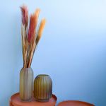 Mini cena. Lado esquerdo, mesas laterais decoradas com dois vasos ovais de vidro fumê com ramalhete de pluma marsala. Itens em fundo azul.