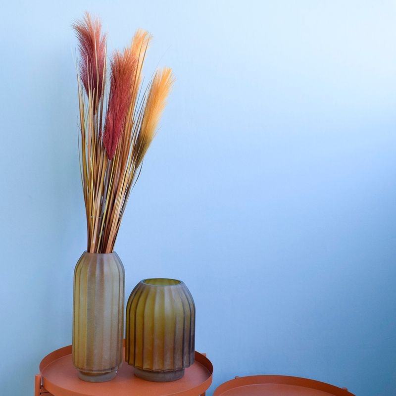 Mini cena. Lado esquerdo, mesas laterais decoradas com dois vasos ovais de vidro fumê com ramalhete de pluma marsala. Itens em fundo azul.