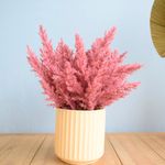 No centro, arranjo de flores secas na cor pink em vaso canelado areia sobre mesa de madeira em fundo azul