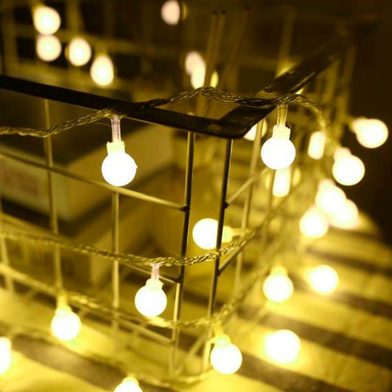 Foco aproximado nas mini lampadas acesas com iluminação amarelada apoiada em grade