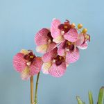 No centro, foco aproximado e detalhado com 6 flores de orquidea artificial rosa em fundo azul