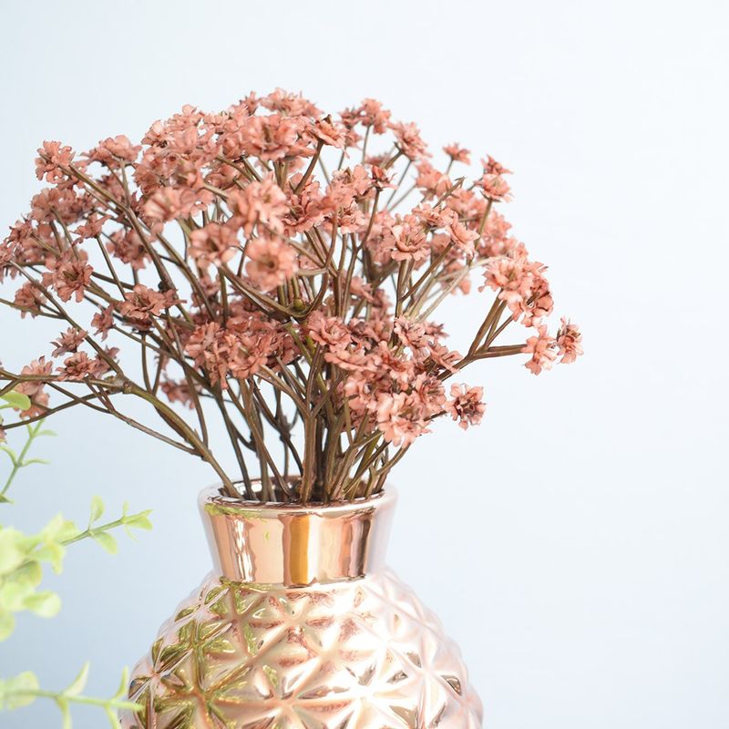 No centro, foco aproximado e detalhado do arranjo de mosquitinho marsala no vaso tipo moringa em vidro espelhado rose em fundo azul
